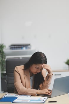 Portrait of tired young business Asian woman work with documents tax laptop computer in office. Sad, unhappy, Worried, Depression, or employee life stress concept photo