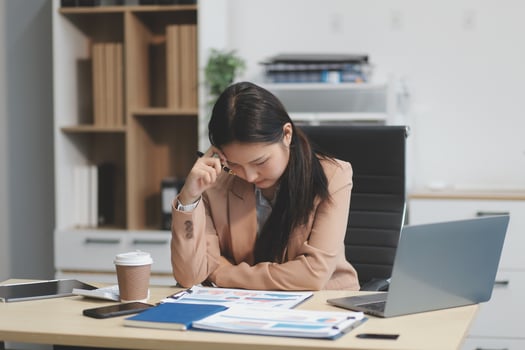 Portrait of tired young business Asian woman work with documents tax laptop computer in office. Sad, unhappy, Worried, Depression, or employee life stress concept photo