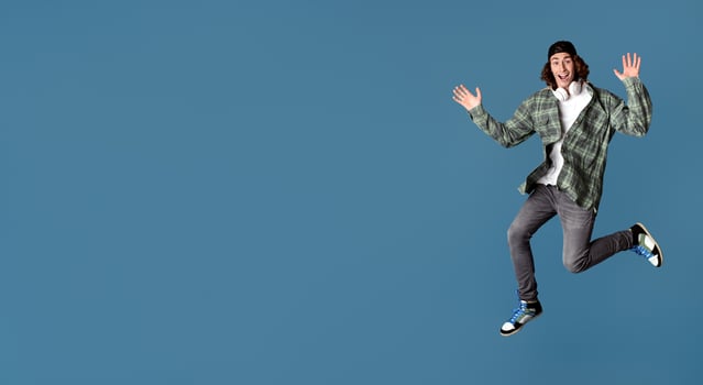 Music is life. Excited teenage guy with headset jumping on color background photo