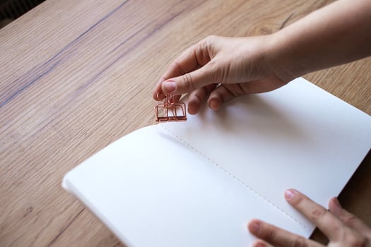 Hand Clipping a Binder to Paperwork on a Desk photo