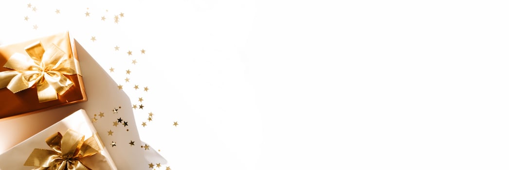 Banner with Christmas gift boxes, adorned with vibrant golden ribbons on white background with shadows photo