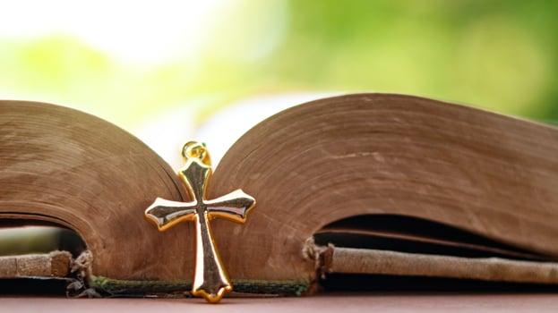 Golden metal cross on an old open book symbolizing the spread of Jesus Christs love among Christians reflecting faith devotion and the importance of Christian teachings. photo