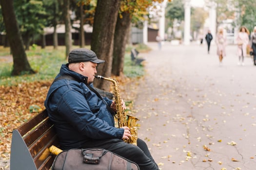 A saxophonist performs in a serene park during autumn while seated on a bench photo