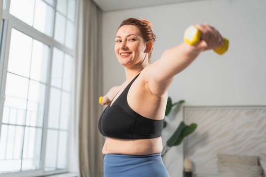 Fitness workout training. Woman picking up dumbbells. Plus size female doing sports exercise at home indoor. Girl in sportswear have workout weight training for weight loss. Sport and fitness photo