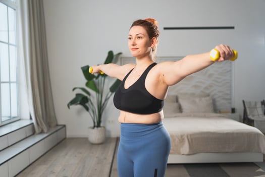 Fitness workout training. Woman picking up dumbbells. Plus size female doing sports exercise at home indoor. Girl in sportswear have workout weight training for weight loss. Sport and fitness photo
