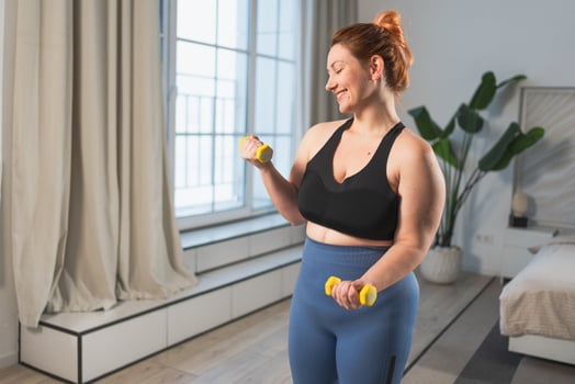 Fitness workout training. Woman picking up dumbbells. Plus size female doing sports exercise at home indoor. Girl in sportswear have workout weight training for weight loss. Sport and fitness photo