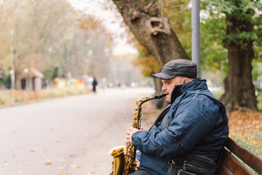 A saxophonist performs in a serene park during autumn while seated on a bench photo