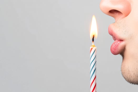 A man blowing out a candle with a birthday candle photo