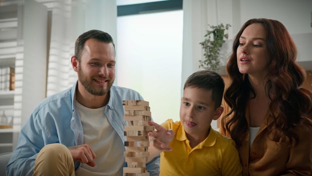 Cheerful happy Caucasian family loving caring mother father playing board game with son at home kid boy enjoying play wooden tower puzzle with parents in living room couch activity with child together photo