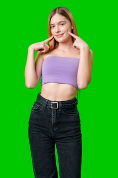 Young Woman Smiling and Touching Cheeks in Front of Green Screen photo