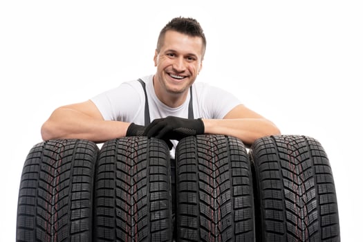 Mechanic leaning on winter tires smiling at auto repair shop photo