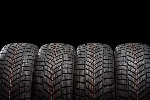 Four winter tires standing on black background photo