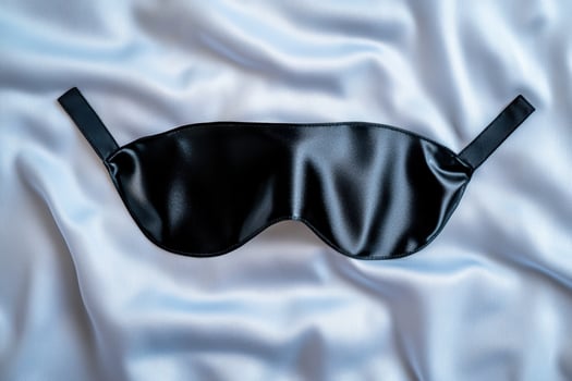 black leather sleep mask on white satin fabric photo