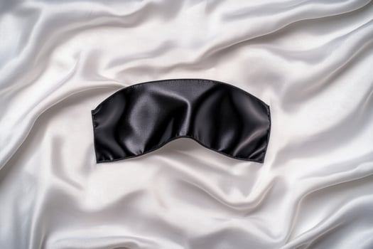 black sleep mask on white satin fabric photo