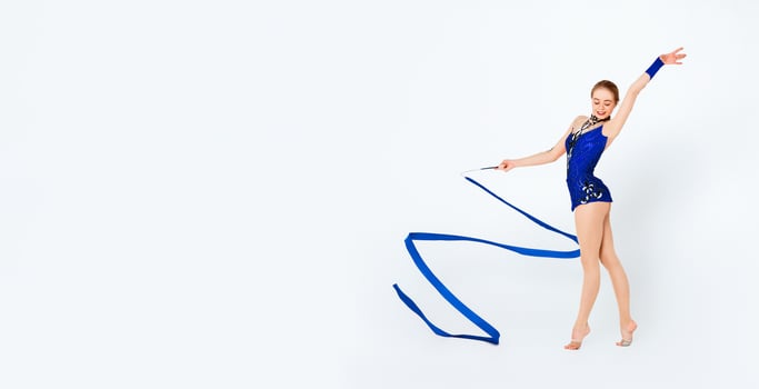 Smiling young sportswoman with gymnastic ribbon practicing on white background photo