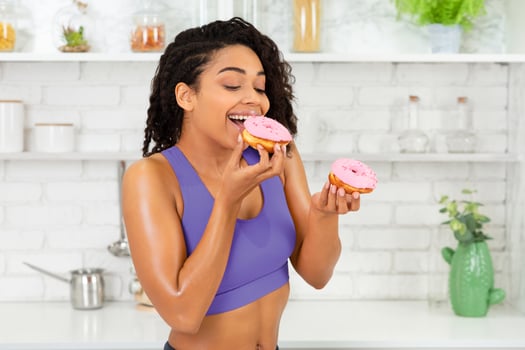 Enjoying Dessert. Happy black sporty girl eating cake, biting sweets, loft kitchen interior, free space for ad photo