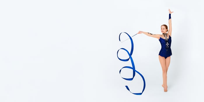 Professional young gymnast in leotard with ribbon on white background photo