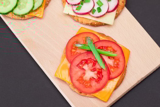 Different Cracker Sandwiches with Tomato, Cucumber, Radish and Cheese on Cutting Board. Easy Breakfast. Diet Food. Quick and Healthy Sandwiches. Crispbread with Tasty Filling. Healthy Dietary Snack photo