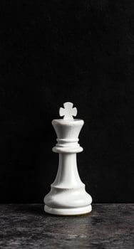 White chess king piece on dark background photo
