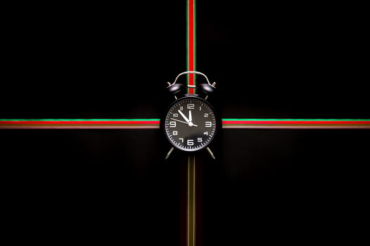 The alarm clock puts in the middle of green and red color ribbon on black background for Black Friday shopping day concept. photo