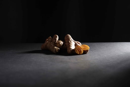 Fresh turmeric root and slices in wooden bowl isolated on dark background, turmeric Curcuma longa Linn, spice concept photo