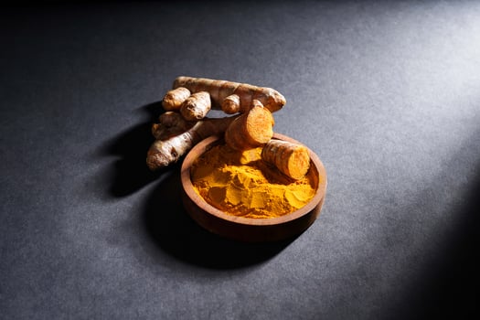 Fresh turmeric root and turmeric powder in wooden bowl, turmeric isolated on dark background, spice concept photo