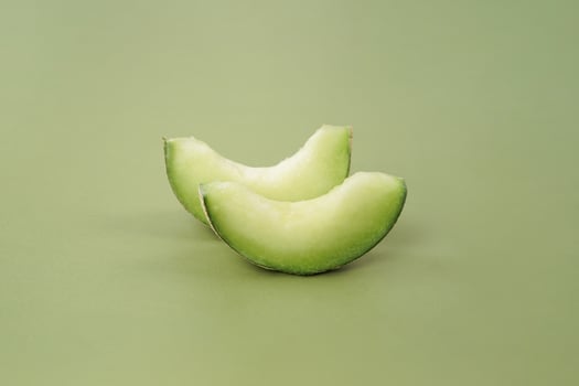 Green cantaloupe melon with cut slice isolated on green background, green melon photo