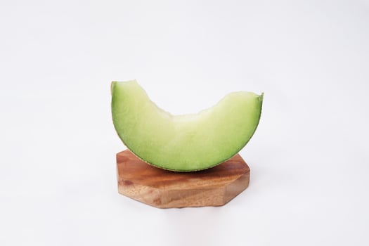 Green cantaloupe melon slice in wooden bowl isolated on white background, green melon photo
