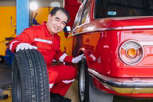 Senior professional Asian male mechanic garage worker happy working tyre wheels replacing car tire maintenance service photo