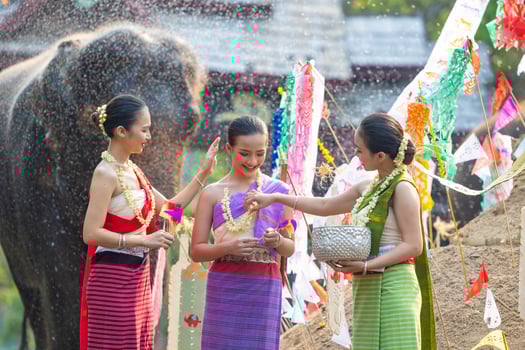 Songkran festival. Northern Thai people in Traditional clothes dressing splashing water together in Songkran day cultural festival with elephant background. photo