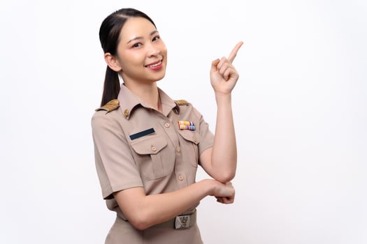 A woman in a Thai asian teacher uniform is pointing to the empty space with a smile on her face. photo