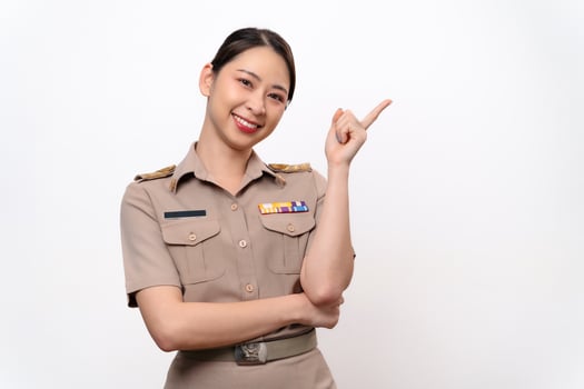 A woman in a Thai asian teacher uniform is pointing to the empty space with a smile on her face. photo