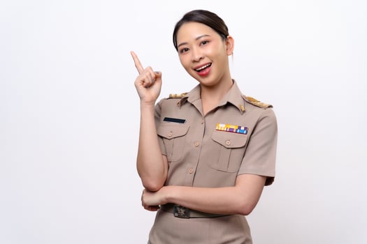 A woman in a Thai asian teacher uniform is pointing to the empty space with a smile on her face. photo