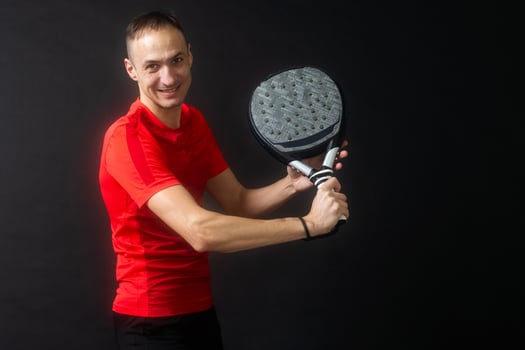 Man plays paddle tennis and poses in studio photos on white black background