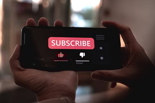Close-up view of a woman using a smartphone to press red subscribe button on online media. Concepts of technology and following news, hot trends and new content on social media photo