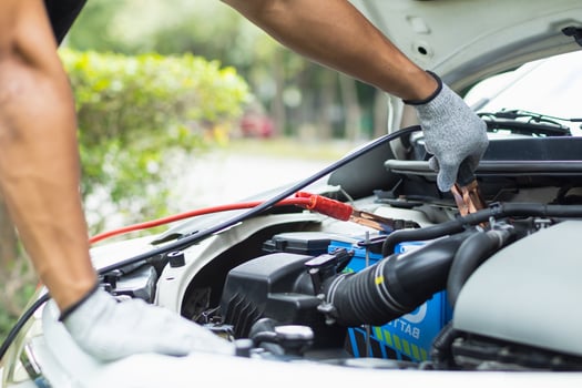 mechanic from the service center is helping to jump start the car battery for customer who has a deteriorated battery and cannot start the car. Jump starting the battery helps to continue the journey photo