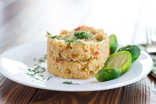 homemade cooked bulgur with Brussel sprouts in a plate, on a wooden table photo