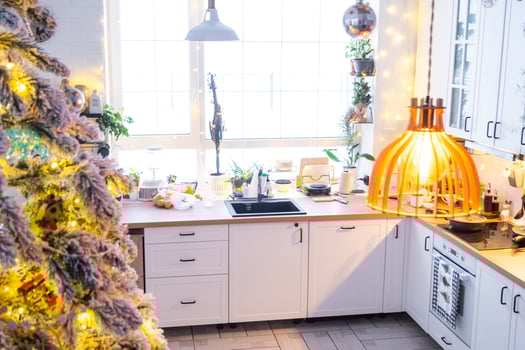 Christmas decor in white kitchen, modern rustic interior with a snowy Christmas tree and gold fairy lights. New Year, Christmas mood, cozy home. photo