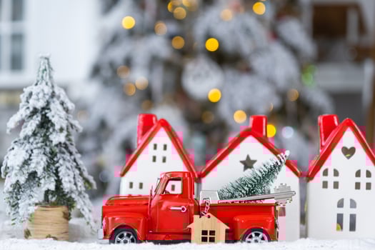 Key on Christmas tree and tiny house with a red roof with Christmas decor in red retro car on table . Gift for New Year. Insurance, moving to new house, mortgage, rent and real estate photo