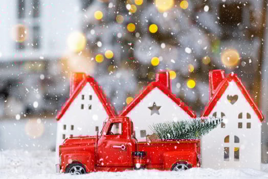 Key on Christmas tree and tiny house with a red roof with Christmas decor in red retro car on table . Gift for New Year. Insurance, moving to new house, mortgage, rent and real estate photo