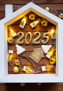 Golden figures number 2025 and tiny home on background of cozy windows of a house with warm light with festive decor of stars,snow and garlands. Greeting card, Happy New Year, cozy home photo