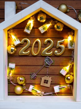 Golden figures number 2025 and tiny home on background of cozy windows of a house with warm light with festive decor of stars,snow and garlands. Greeting card, Happy New Year, cozy home photo