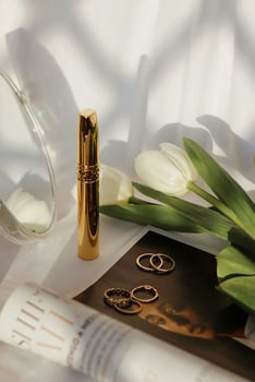 a gold lipstick, a magazine and a bouquet of flowers photo