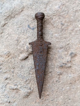 Rusted medieval sword on stone surface photo