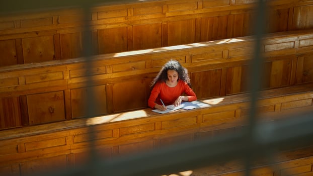 Distant view Caucasian girl student Hispanic woman Latina American female in university college auditorium high school academy writing task homework test exam write in classroom study education learn photo