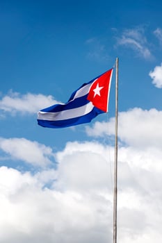 National flag of Cuba on a flagpole against a beautiful sky photo