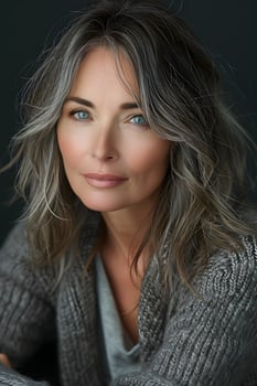 A woman with gray hair and blue eyes is wearing a grey sweater photo