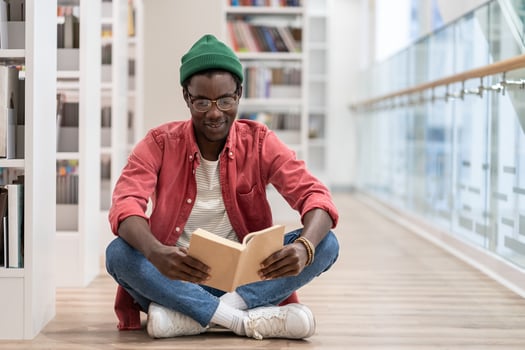 Focused African American guy preparing materials for upcoming lecture reading book in university photo