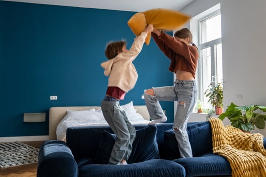 Naughty siblings boy and girl staged pillow fight on couch at home. Fun playing active game together photo