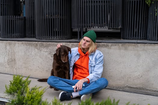 Upset depressed millennial guy sitting on sidewalk with dog, having housing problems photo